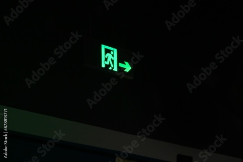 Luminescent green emergency exit sign with arrow in the dark