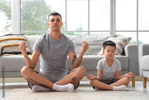 Young man with his little son meditating at home