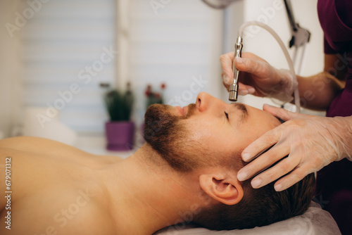 A man at a beautician undergoing a diamond microdermabrasion procedure