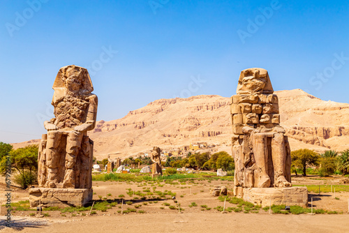 Famous Colossi of Memnon - massive ruined statues of the Pharaoh Amenhotep III. Travel and tourist landmarks. Luxor, Egypt - October 21, 2023.