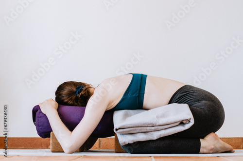Woman doing restorative yoga child's pose with props