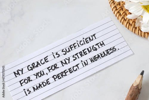 My grace is sufficient to you, for My strength is made perfect in weakness, handwritten Christian quote with flowers and pencil. Faith, trust, and peace in God Jesus Christ (2 Corinthians 12:9 verse).