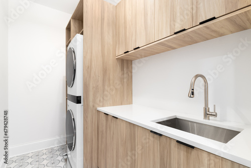 A laundry room with wood cabinets, a white marble countertop, patterned tile floor, and white washer and dryer.