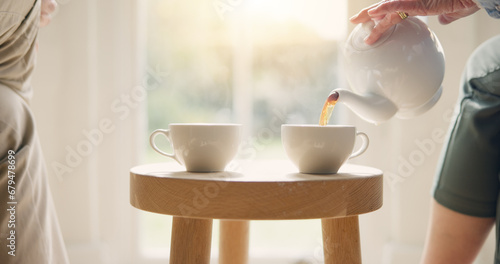 Pot, pour and hands with tea cup in morning, home and closeup on drink, steam and table. Hot, beverage and person with hospitality, service and drinking in the afternoon with friends in living room
