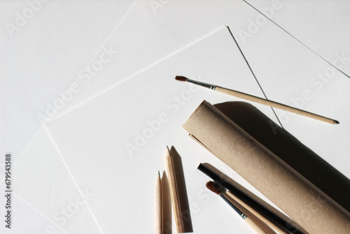 Design Studio Flatlay. Kraft Paper Roll, Sheets of Paper, Graphite Pencils, Small Painting Brushes Arranged on Desk. Drawing, Sketching Mockup. 