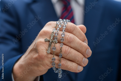 Różaniec owiniety wokół palców dłoni modlącego się człowieka 