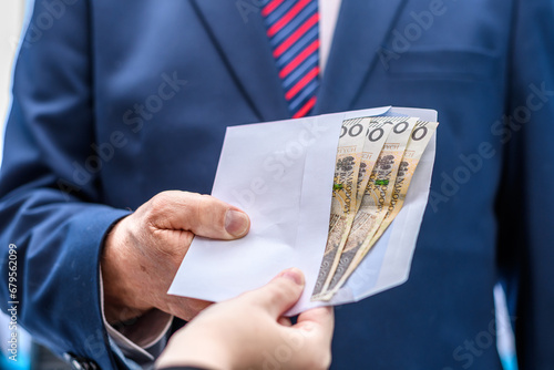 Wręczana koperta z pieniędzmi mężczyźnie ubranemu w elegancki garnitur 