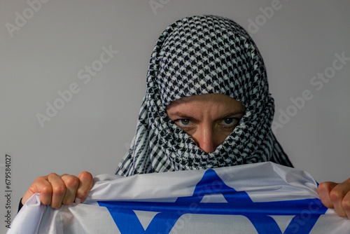 Green-eyed woman with Palestinian headscarf carrying an Israeli flag. Conflict concept
