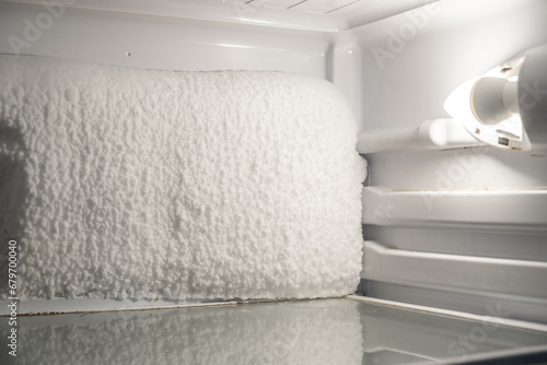 Frozen refrigerator that needs to be defrosted. Block of ice in the empty fridge. empty shelves in the refrigerator. Refrigerator maintenance. 