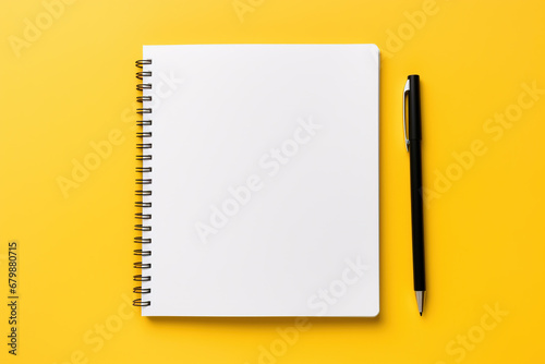 Stock photo of a white tablet with a black notebook and a white pen on a yellow background