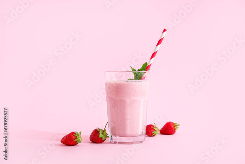 Glass of tasty strawberry smoothie on pink background