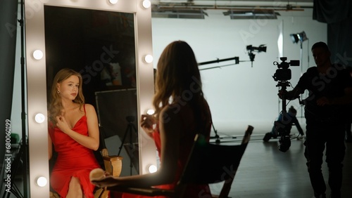 The actress is preparing to film a movie. She sits in front of a mirror on the set and applies makeup to herself. Backstage concept