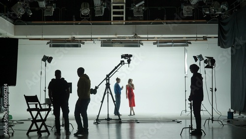 Professional filming pavilion with a white cyclorama. The process of preparing for the shooting of a music video. Director, Cameraman and crew in Backstage.