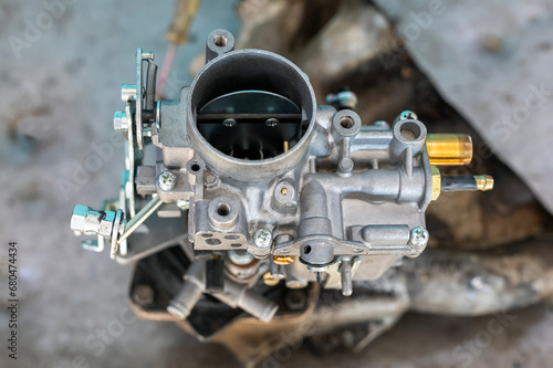 View of automobile carburetor. A carburetor (also spelled carburettor or carburetter) is a device used by a gasoline internal combustion engine to control and mix air and fuel entering the engine.