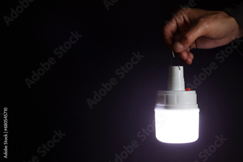 A man's hand holds a portable rechargeable LED emergency light