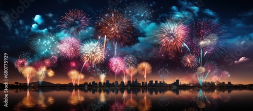 Colorful fireworks of various colors over the cityscape and water reflection