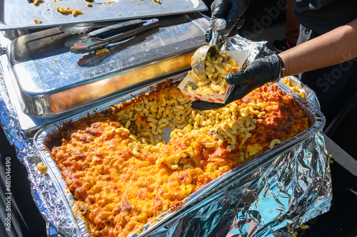 Hands Serving Jerk Chicken Mac and Cheese at the Poboy Festival on Oak Street in New Orleans, LA, USA