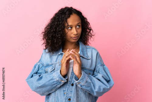 Teenager cuban girl isolated on pink background scheming something