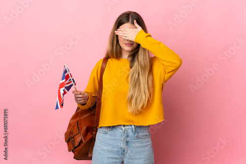 Young blonde woman holding an United Kingdom flag isolated on white background covering eyes by hands. Do not want to see something