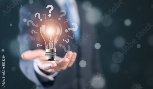 Businessman hand holding glowing lamp lightbulb with question mark