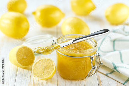 Jar of tasty lemon jam on a white wooden table.