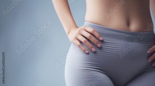 Close up of waist, belly and genital area of young woman wearing light gray tights Isolated on white background. 