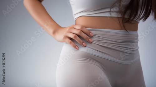 Close up of waist, belly and genital area of young woman wearing light gray tights Isolated on white background. 