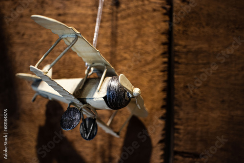 small tin biplane, antique toy hanging on rustic wooden background