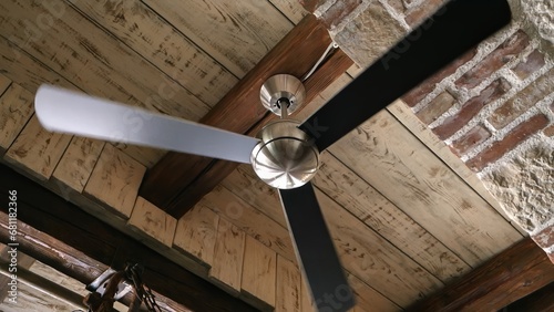 Old ceiling fan lamp spinning in the antique interior with brick walls and wooden roof