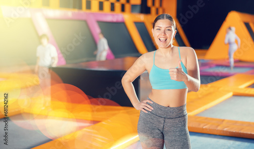 Positive young woman in sport clothes standing expressing different poses in trampoline arena
