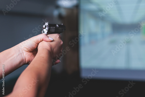 Process of shooting target at the shooting rifle range, women practicing with hand gun pistol at shooting gallery, firearms training, pointing weapon on digital screen, live fire digital targeting