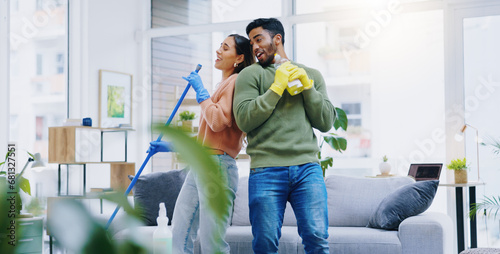 Happy couple, dancing and singing while cleaning living room together for fun disinfection or hygiene at home. Man and woman enjoying housekeeping, germ and bacteria removal in lounge at house