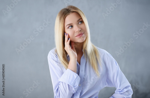 Portrait of a sexy woman in a man's shirt wearing on a gray background looks at the camera and smiling look advice to give wants objections are not accepted.