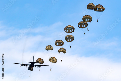 Military parachutist paratroopers parachute jumping out of an air force plane.