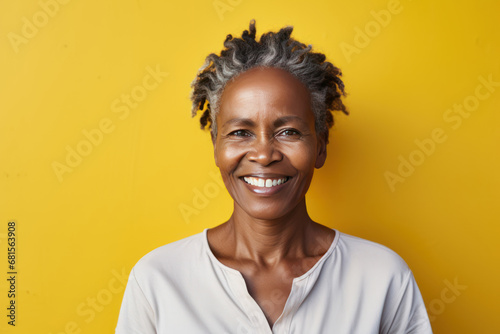 Studio portrait of a smiling woman in front of a yellow wall.