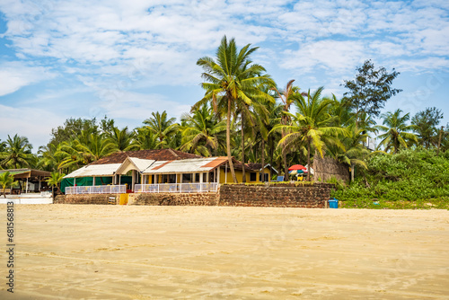 coconut trees on ocean coast near tropical shack or open cafe on beach with sunbeds