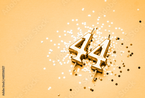 44 years birthday celebration festive background made with golden candle in the form of number Forty four lying on sparkles.