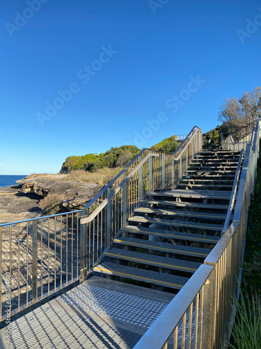 Wooden stairway to the sea. Boardwalk to the beach. Bridge and walkway near the blue turquoise ocean. Pier in the sea. Wood fence.
