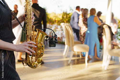 A woman musician plays the saxophone at an open-air party. 