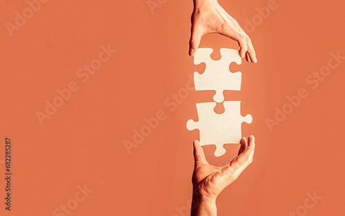 Closeup hands of man connecting jigsaw puzzle. Two hands trying to connect couple puzzle. Hand connecting jigsaw puzzle. Man hands connecting couple puzzle piece