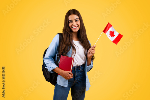 Happy caucasian teenager student woman, with Canada flag and book, enjoy exchange study