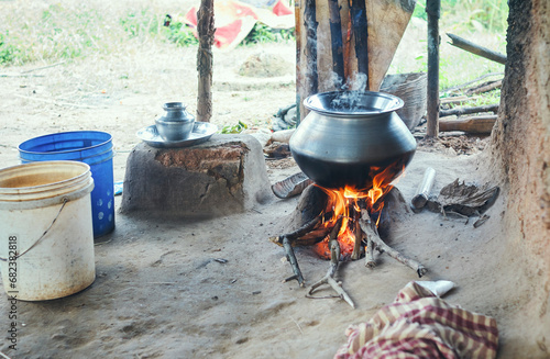 rice being cooked in aluminium utensil with logs burning under mud chulha (clay stove). At a tribal village in Bandwan, Purulia, where most people belong to economically backward class.