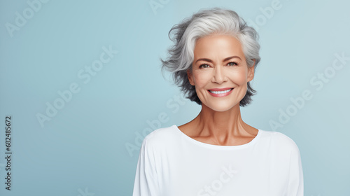 beautiful elderly woman model with beautiful gray hair posing in the studio on a pastel blue background. advertising beauty photo shoot. health and graceful aging. copy space. banner