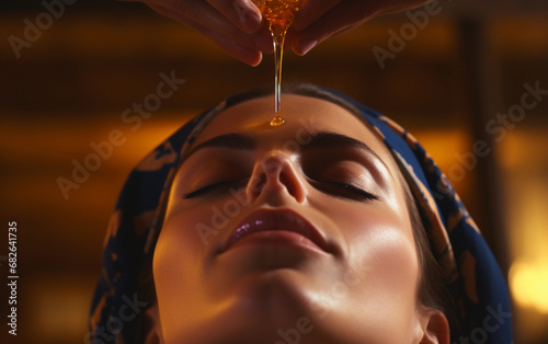 Ayurvedic oil treatment on woman forehead in spa