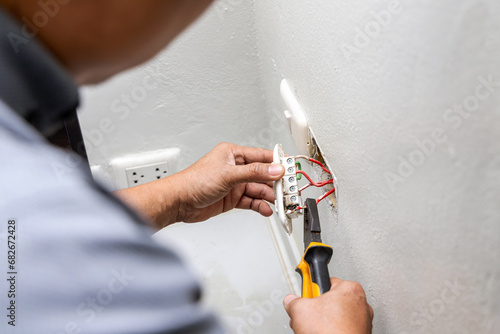 Close-up hand of electrician holding electric outlet plug for repair or maintenance and fixing in office room. Dangerous of electric spark from short circuits and fire in house.