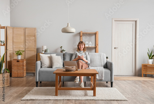 Young woman with cup of tea relaxing on sofa at home