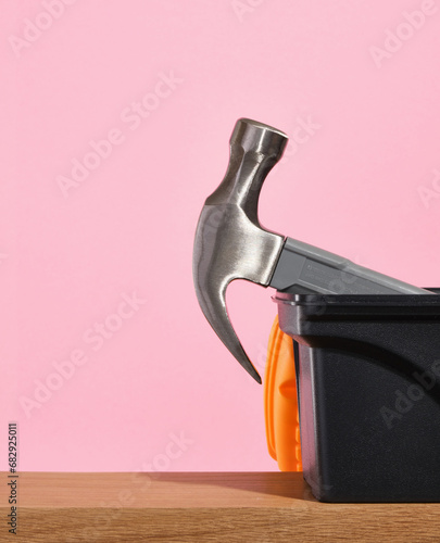 The hammer is seen from the plastic tool box on a pink background. Construction and manufacturing tools. Copy space for text.