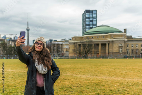 A girl talking selfie of her self with buildings in the background.