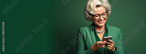 mature woman smiling and looking at phone screen, banner with place for text in green tones