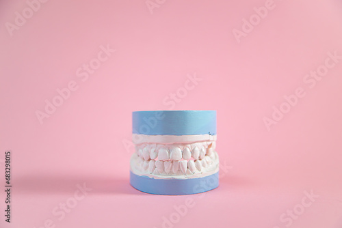 Plaster model of teeth on a pink background.